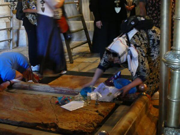 Tourists placing souvenirs on the Stone of Annointing in the Church of the Holy Sepulchre